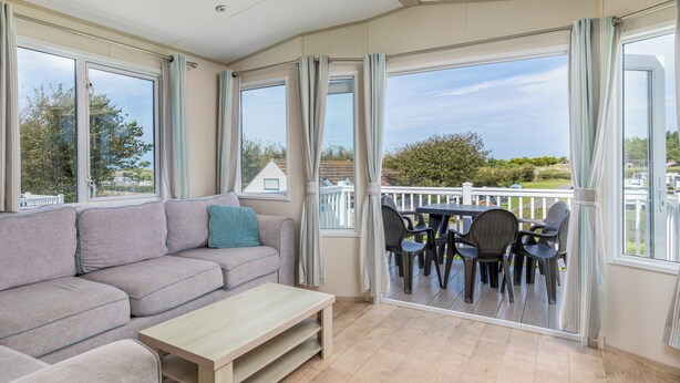A room with a sofa, a small table, and a balcony with chairs.