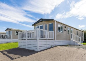 A mobile home with a front deck, a ramp, and a garage door.