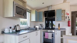 A modern kitchen with a microwave, stove, oven, and a fire blanket sign.