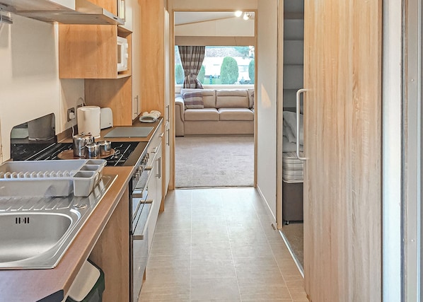 A compact kitchen with a sink, stove, and cabinets, leading to a seating area with a view.