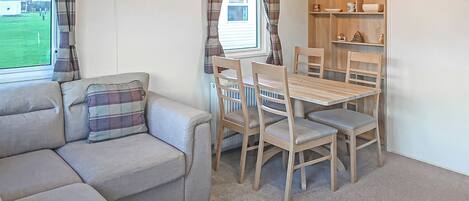 Una habitación acogedora con sofá, mesa de comedor con sillas, un radiador y una estantería con objetos decorativos.