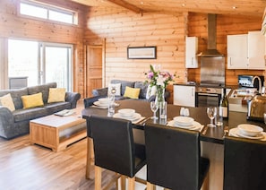 A cozy log cabin interior with a dining area, kitchen, and living room.