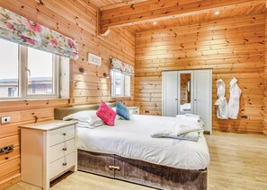 A wooden cabin bedroom with a bed, bedside table, dresser, and a wardrobe. - 2 bedroom accommodation in Withernsea (Withernsea)