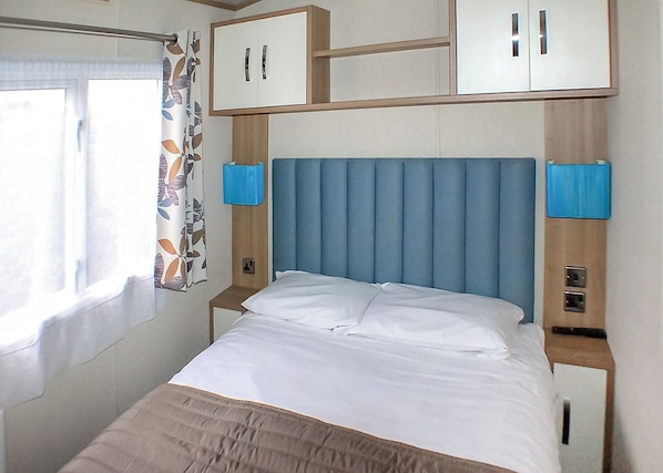 A bed with a blue headboard, white bedding, and two bedside tables with lamps.