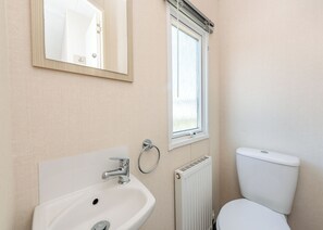 Ein Badezimmer mit Waschbecken, Toilette, Spiegel und Fenster.