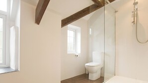 Une salle de bain moderne avec une douche à parois de verre, des toilettes blanches et une baignoire.