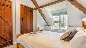 Une chambre avec un grand lit, une armoire en bois et une lucarne.