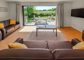 A living room with a sofa, a coffee table, and a TV. - Single storey cottage in its own secluded setting away from the lodges. (North Tamerton, Bude)