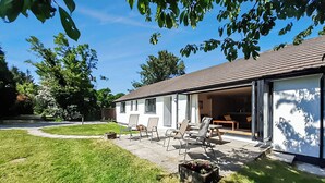 Ein modernes Haus mit Terrasse, Sitzgelegenheit im Freien und Garage.