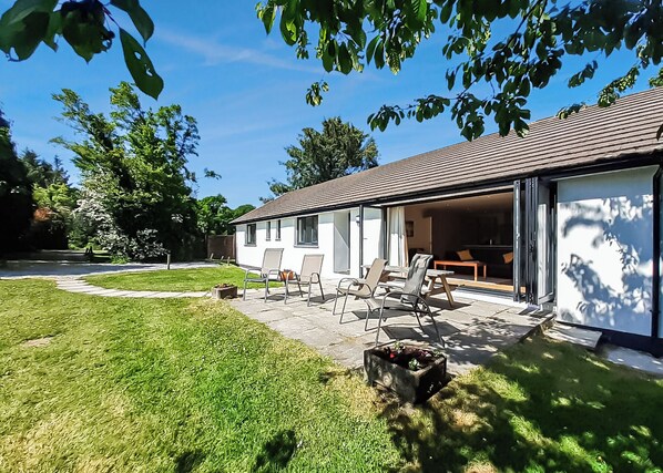 A modern house with a patio, outdoor seating, and a garage.