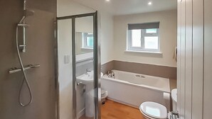 Ein Badezimmer mit Duschkabine, Badewanne, Toilette und Fenster.