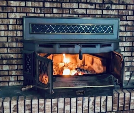 A wood-burning fireplace with a metal grate and a chimney.