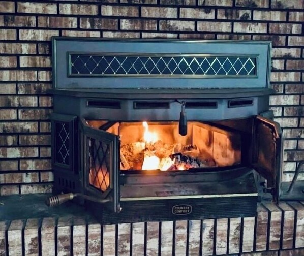 A wood-burning fireplace with a metal grate and a chimney.