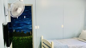 Un dormitorio con cama, un mural del cielo nocturno, un ventilador de pie y un televisor.