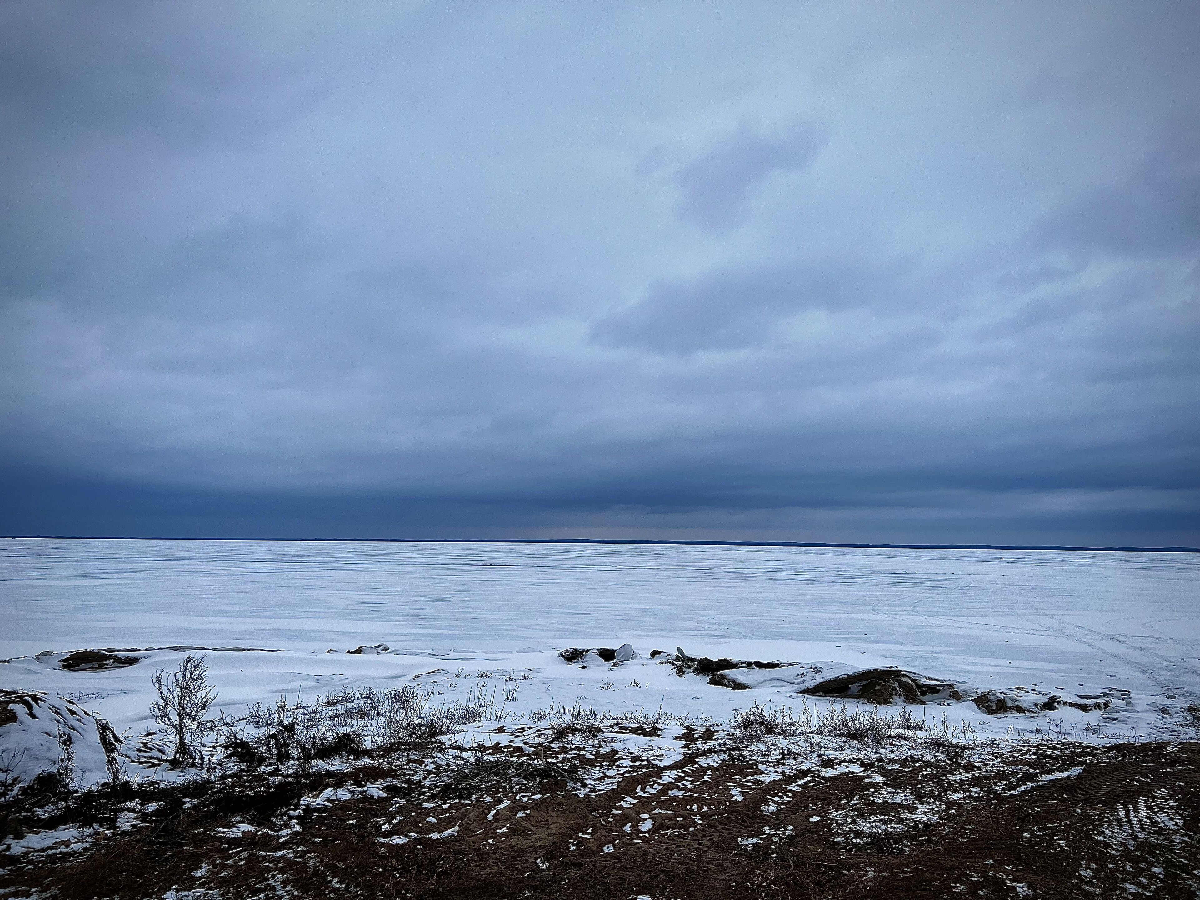 Un paysage enneigé avec un horizon plat et un ciel nuageux.