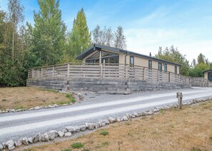 A building with a sloped roof, wooden fence, and a gravel driveway.