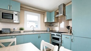 Una cocina con gabinetes color turquesa, un microondas, una estufa y un lavamanos.