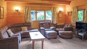 A log cabin interior with a sofa set, ottoman, coffee table, and a television on a stand. - Spacious timber lodge with one double and one single in one room. (Kentisbeare, Nr Cullompton)