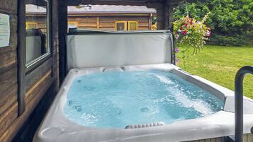 Un bain à remous avec vue sur un chalet en bois et un jardin.