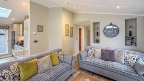 A modern living room with two sofas, a dining area, and a kitchen. - 4 bedroom accommodation in Tenby (Tenby)