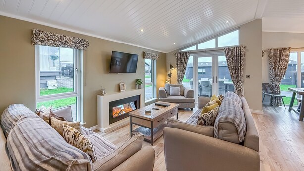 A spacious living room with a fireplace, sofas, a coffee table, and a TV. - 4 bedroom accommodation in Tenby (Tenby)