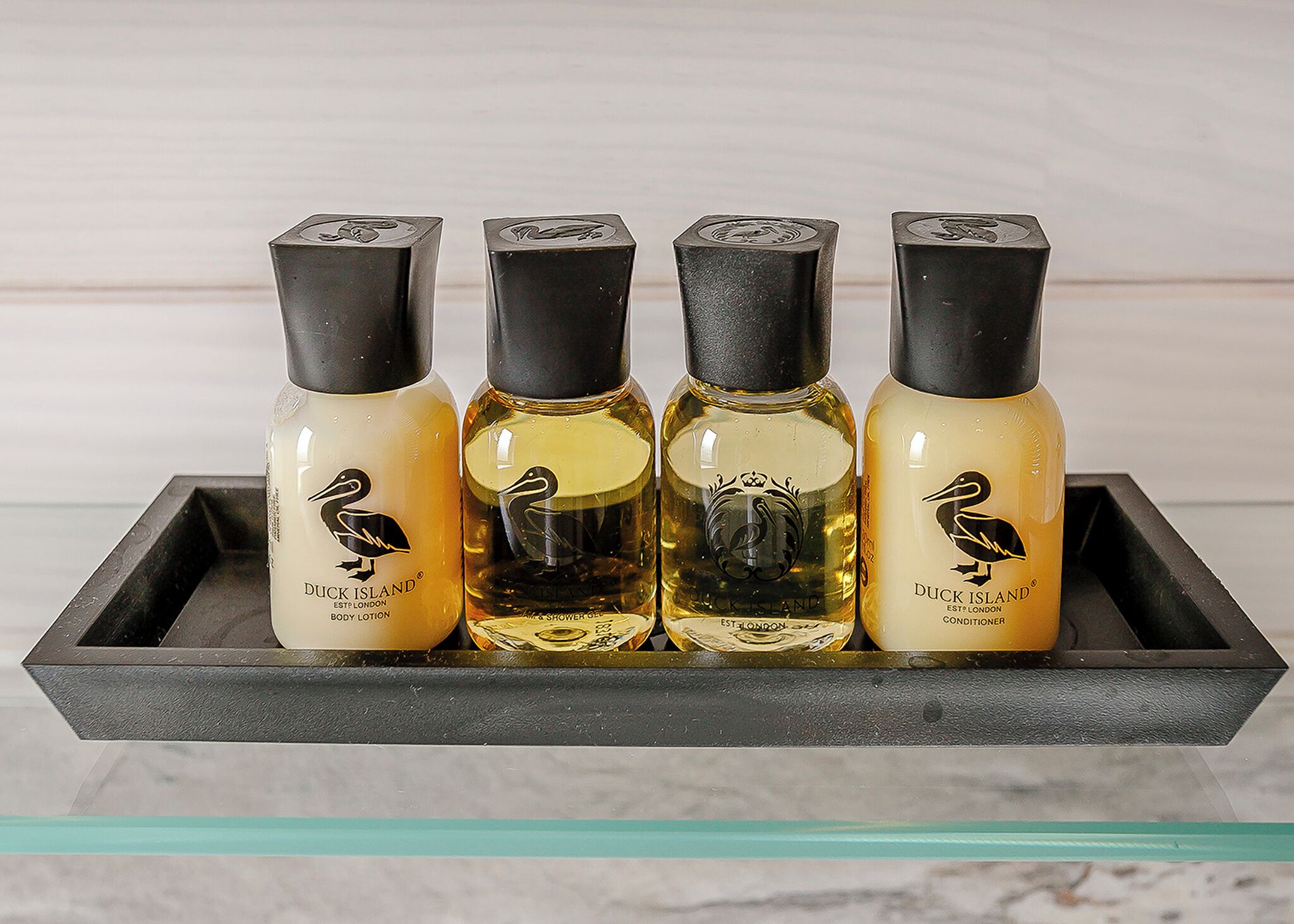Four bottles of Duck Island body lotion, shower gel, and conditioner on a black tray.