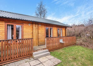 A wooden cabin with a porch, large windows, and a metal roof.