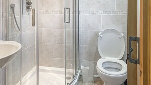 Une salle de bain avec une douche à parois de verre, des toilettes et un lavabo.