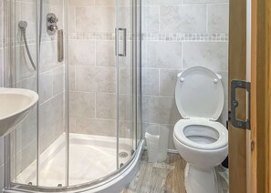A bathroom with a glass-enclosed shower, a toilet, and a sink.