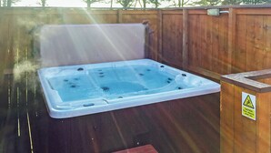 Un bain à remous avec jets, une terrasse en bois et un panneau d’avertissement.