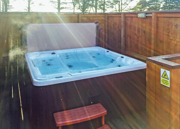 A hot tub with jets, a wooden deck, and a caution sign.