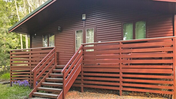 Une cabane avec une façade en bois, une véranda et un escalier menant à l’entrée.