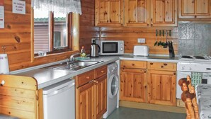 Une cuisine compacte avec des meubles en bois, un lave-linge, un four à micro-ondes et un évier.