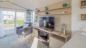 A modern living room with a TV, sofa, and fireplace. - Stylish and comfortable holiday home featuring your own private hot tub. (Laurenkirk)