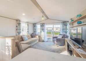 Ein modernes Wohnzimmer mit einer Couch, einem Sessel, einem Fernseher und einem Kamin.