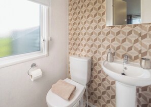 Une salle de bain avec des toilettes, un lavabo et une fenêtre.