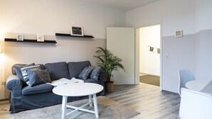 A modern living room with a grey sofa, a white coffee table, and a potted plant.