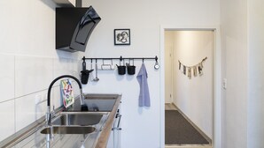 A modern kitchen with a stainless steel sink, a black range hood, and a hanging pot rack.