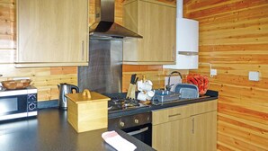 A kitchen with wooden cabinets, a stove, a microwave, and a sink.