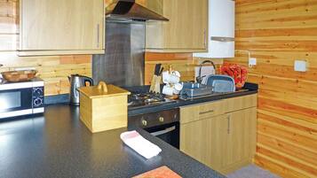 Une cuisine avec des meubles de rangement en bois, une cuisinière, un four à micro-ondes et un évier.