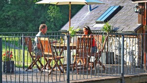 An outdoor patio with a table and chairs, a metal fence, and a house in the background. - 2 bedroom accommodation in Pontyberem, Carmarthenshire (Pontyberem, Carmarthenshire)
