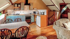 A cozy kitchen with a dining area, wooden flooring, and a loft-style ceiling. - 2 bedroom accommodation in Pontyberem, Carmarthenshire (Pontyberem, Carmarthenshire)