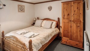 A bedroom with a wooden bed, a wardrobe, and a small bedside table with a lamp. - 2 bedroom accommodation in Pontyberem, Carmarthenshire (Pontyberem, Carmarthenshire)