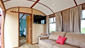 Ein gemütliches Interieur mit einer Couch, einem Fernseher und einer Holztür zu einem anderen Raum.