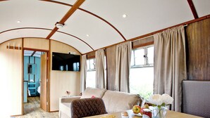 Ein gemütliches Interieur mit einem Holztisch, gedeckt für das Frühstück, einer Couch und einem an der Wand befestigten Fernseher.