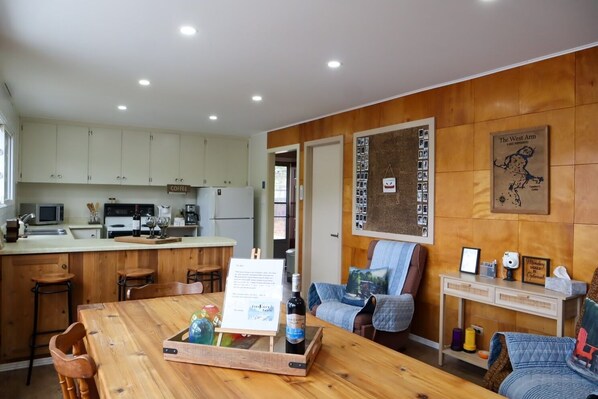 A cozy kitchen with wooden cabinets, a central island with bar stools, a dining area with a wooden table, and a seating area with a cushioned bench.