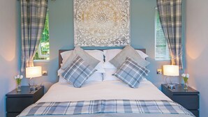 A bedroom with a bed, two nightstands, a decorative headboard, and plaid curtains.