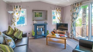 A living room with a sofa, a coffee table, a fireplace, a TV, and curtains.