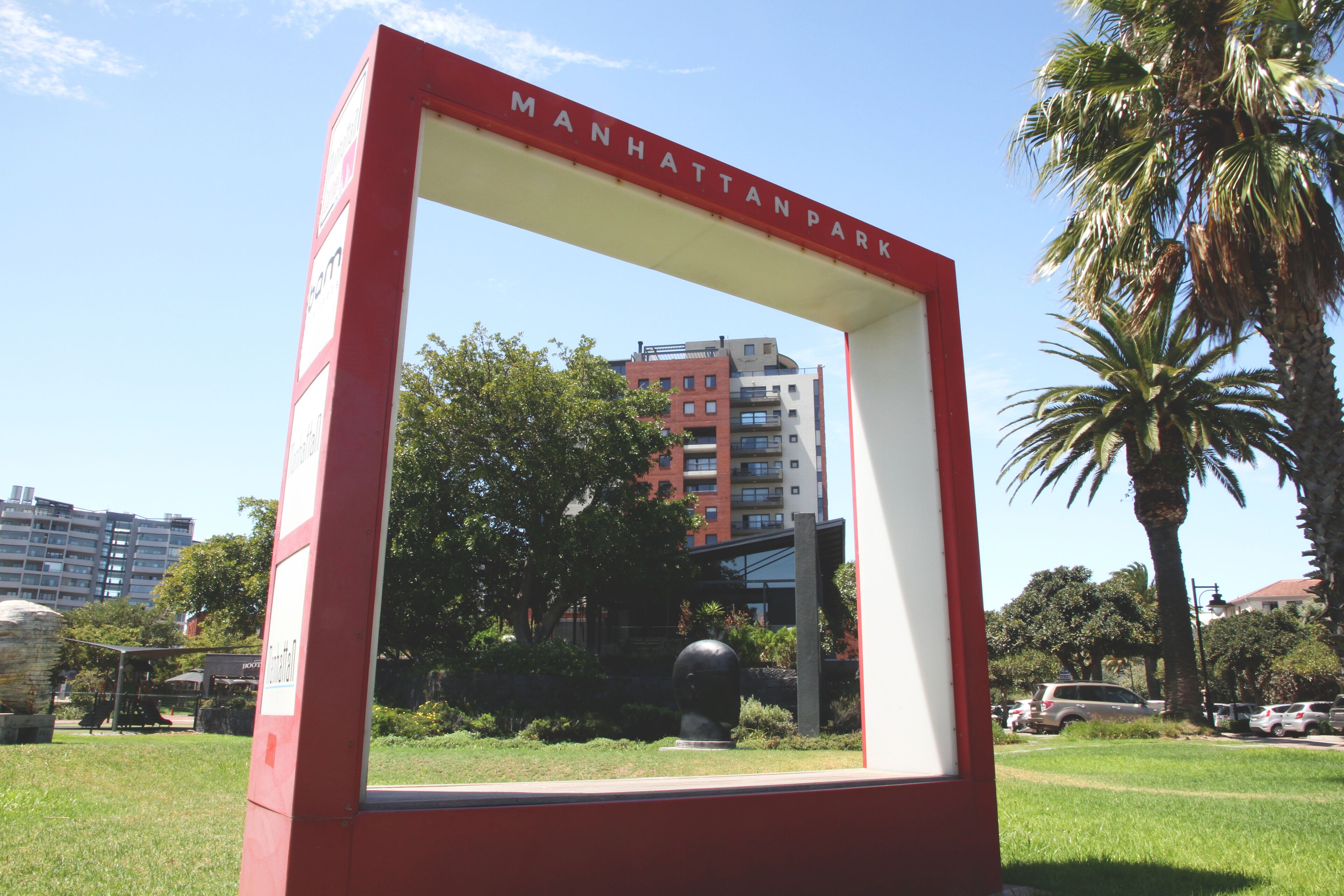A framed view of Manhattan Park with a red border and a clear sky in the background.
