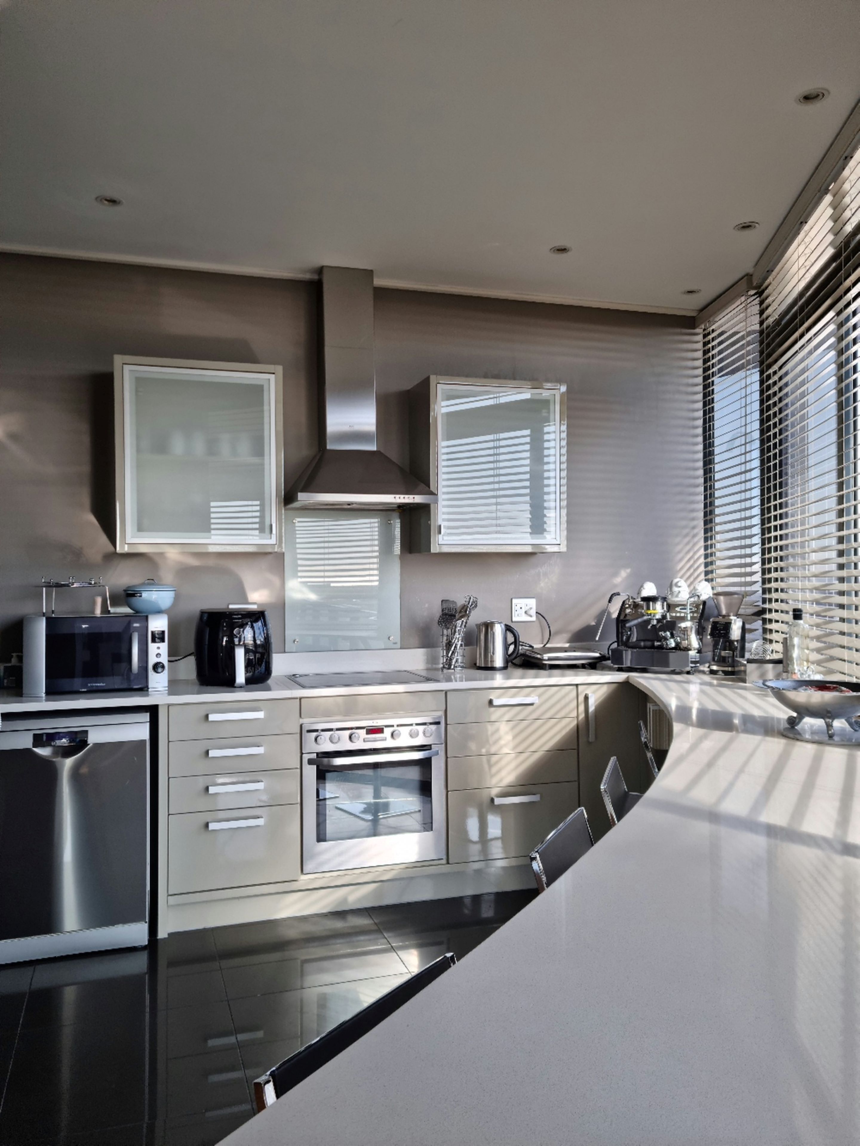 A modern kitchen with stainless steel appliances, a built-in oven, and a large window with blinds.